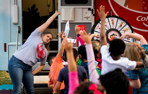 Student leads a group of young students in a stretch